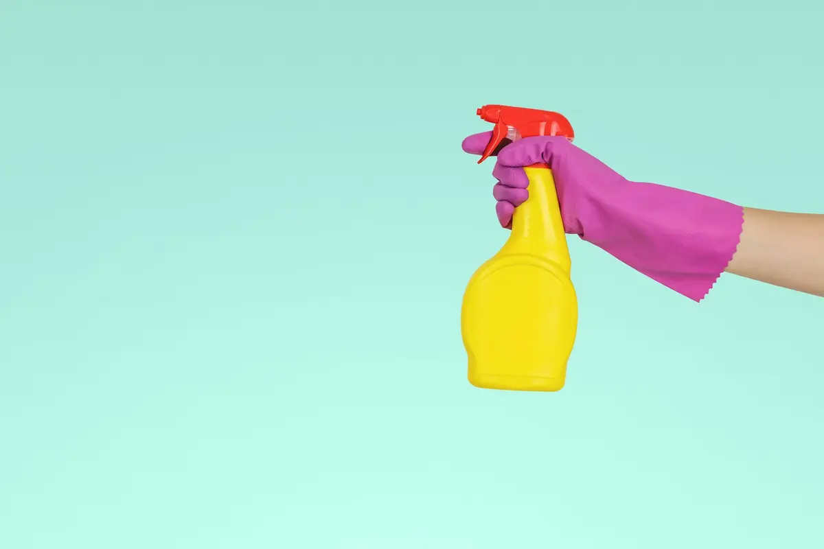 Cleaning spray bottle held in a gloved hand
